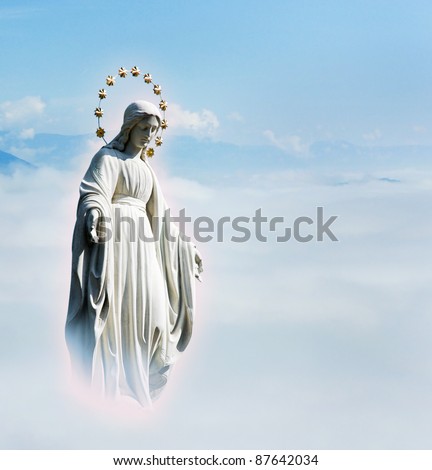 Blessed Virgin Mary at the sky background. Mother Mary statue. Holy phenomenon of Holy Maria in the light of glow in the sky above the clouds.