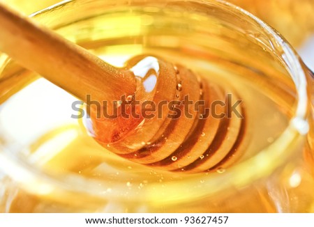 Bee honey with wooden dipper. Honey\'s dessert - honey stick on golden background.