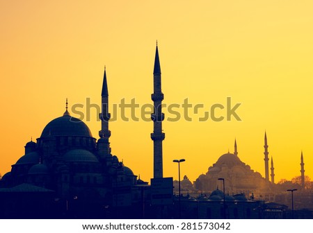 Silhouettes of Yeni Cami Mosque and Suleymaniye Mosque at sunset, soft light effect. Panoramic view of muslim architecture landmarks with minarets, district of Sultanahmet in old Istanbul.