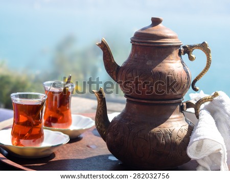 Turkish tea with authentic glass cup and copper tea kettles. Two cups of turkish tea served in traditional style with view on Bosporus. Istanbul cafe with oriental culture of the street food.
