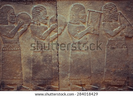 Stone wall with ancient musicians, who is playing on antique musical instruments. Relief with assyrian musical scene - art and culture of Mesopotamia and Babylonia, Istanbul museum.