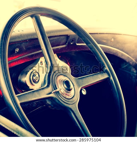 Interior of an old automobile with steering wheel closeup. Retro car in soft light effect. Detail  of oldtimer automobile - vintage photo of inside car salon.