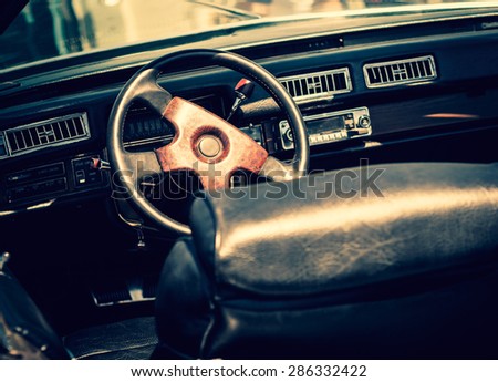 Retro car in vintage toned film effect. Interior of an old automobile with a steering wheel and dashboard. Retro design of the seventies - american car style, inside of car salon.