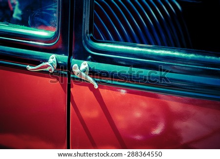 Door handles of an old car. Old red car with ancient door handle - detail of retro car. Vintage auto - side view of antique automobile.