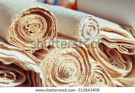 Handmade textile in retro style - natural  fabric of flax and cotton. Canvas and burlap in rolls closeup - homespun fabric of handwork.