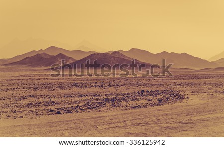 Sahara desert - mountain landscape and stone hills silhouettes on a horizon. Exotic adventure in Arabian desert, extreme travel to Egypt. Sandstorm in african desert. Extreme safari on off-road car.
