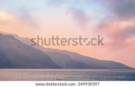 Mountains landscape at sunrise - cloudy sky in pastel colors for your design, serenity and rose quartz. Romantic mountain landscape - seaside view and blue hills silhouettes in a fog.