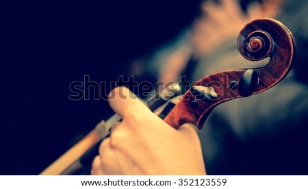 Violinist hand and his music instrument. Violin and bow in the hands of the musician on blurred background. Violin at soft focus, instagram filter colors.