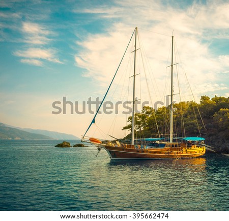 Sea voyage on classic yacht - luxury lifestyle in summer. Picturesque seashore with sailing vessel near island. Nautical landscape with wooden sailboat in retro style.