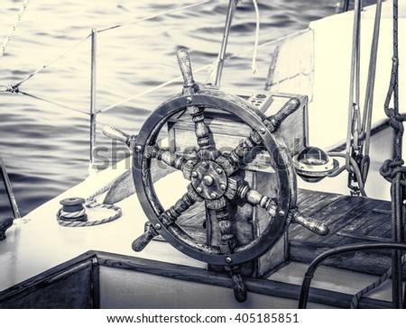 Vintage yacht in retro style. Steering wheel on the old sailboat. Sea voyage of the sailing vessel. Travel at sail boat with a wooden helm in front. Ship wheel on the old yacht.