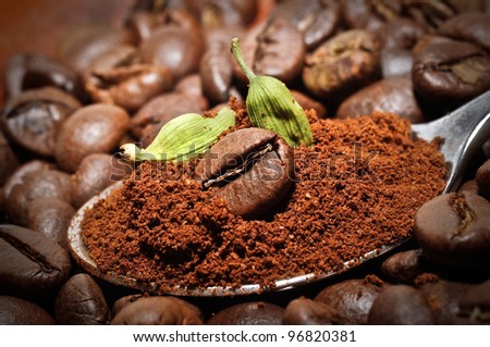 Arabic coffee beans with green cardamom - traditional oriental drink. Closeup of coffee bean at roasted coffee heap.