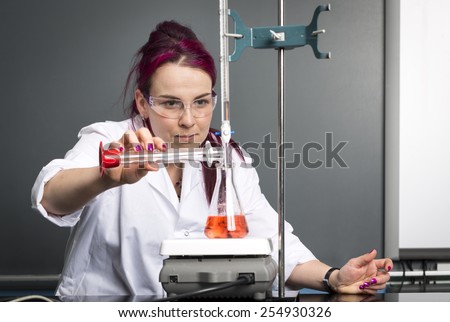 a woman wearing a white coat and safety glasses is doing an experiment in a school laboratory