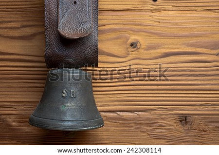 old cowbell with leather strap on pine wood