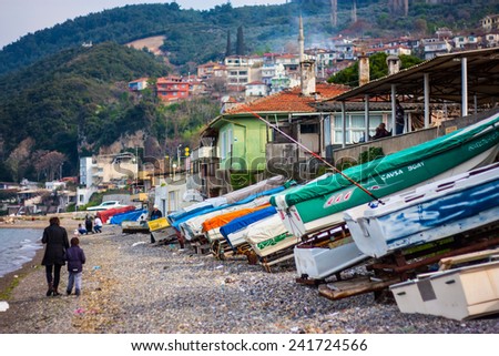 Landscape. The fishing town of Mudanya, Turkey. Pebble beach, boats stacked for drying. People walk along the beach. In the background mountains.