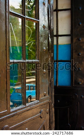 Building, facility. Old door in the house, with the reflection of the street in glasses.