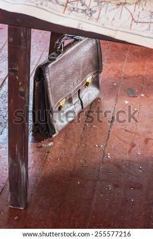 Leather old case under the table with a map on the painted wooden floor. Without the use of filters.