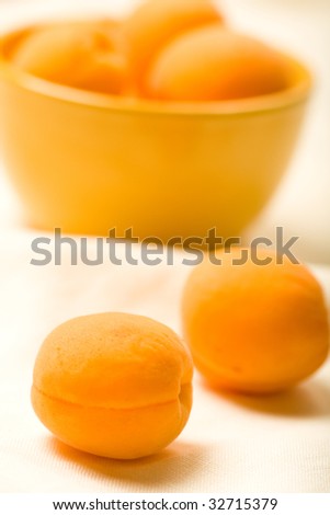 Apricots in yellow bowl on linen table cloth wrinkled to show texture at low depth of field