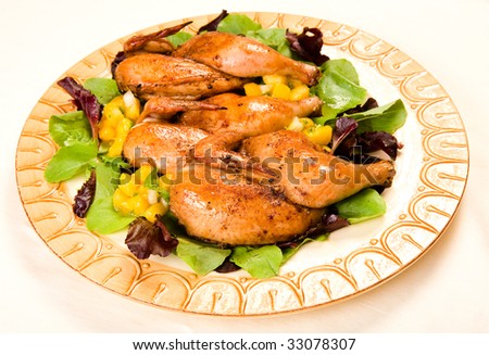 Cornish hen halves served on a bed of lettuce with mango salsa