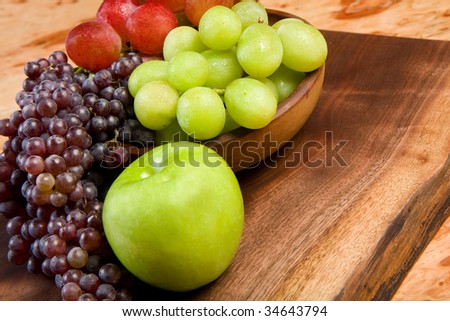 champagne, red globe, and green grapes on natural wood cutting board with apple