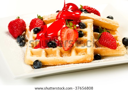 Waffles with fruit and red strawberry syrup