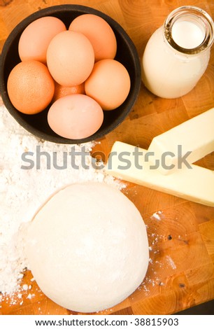 Baking ingredients on cutting board with dough ball