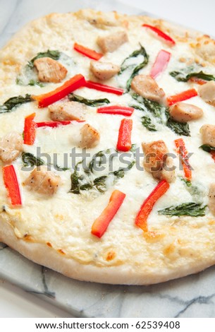Chicken pizza with white sauce, peppers, and basil