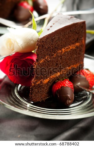 Rich dark chocolate cake with mousse filling accompanied by chocolate covered strawberries and roses