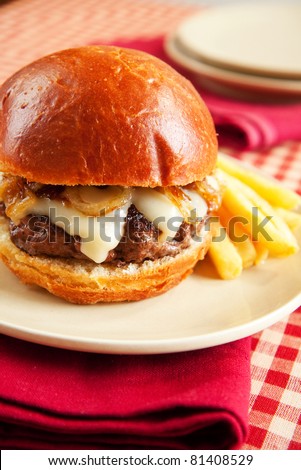 Rare cheeseburger with caramelized onions and melted swiss cheese on large roll