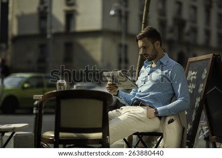 Smart casual outfit man at a coffe shop reading the news paper