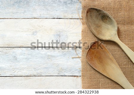 Wooden dipper kitchenware on a sack on a white wooden table of a rustic kitchen. Copy space for editor\'s text.