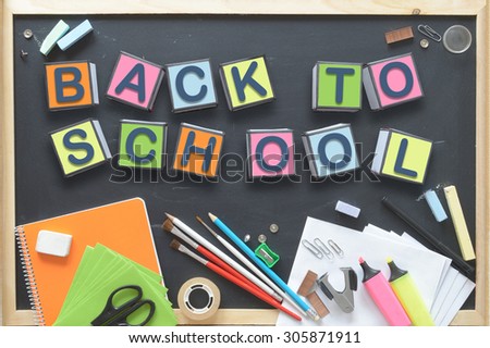 Some cube letters composing the words BACK TO SCHOOL on a blackboard. Some school materials representing the start of a new educational course.