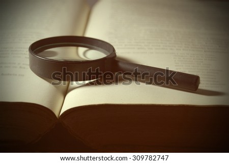 Inspiring scene with a magnifying glass on an open old book representing historical investigations. Romantic reading of the classic books. Blank copy space for the editor\'s text.