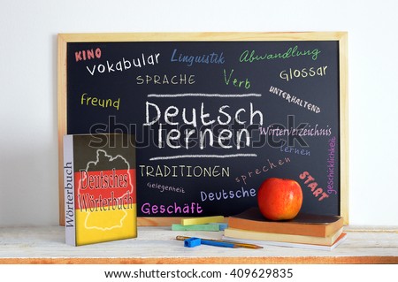 Blackboard in a German language classroom with the message LEARN GERMAN and some other linguistic words.