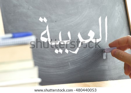 Hand writing on a blackboard in a language class with the text \