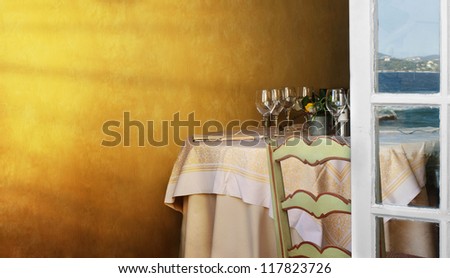 Arranged table in a restaurant and open window. Reflection of the sea on the window .Copy spice on the wall