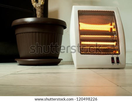 Electric heater with halogen coils. Flower pot and heater on marble slabs