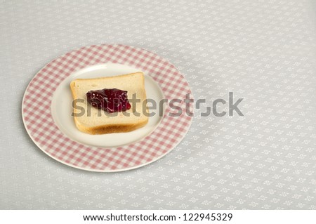 Spread jam on bread. Pink checkered plate