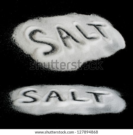 Word Salt on black background written by spilled salt
