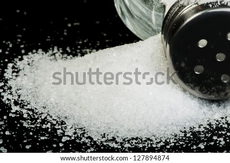 Pile of spilled salt and saltshaker black isolated
