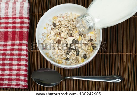 Muesli breakfast in package.Bottle milk and spoon. Pouring milk in a bowl