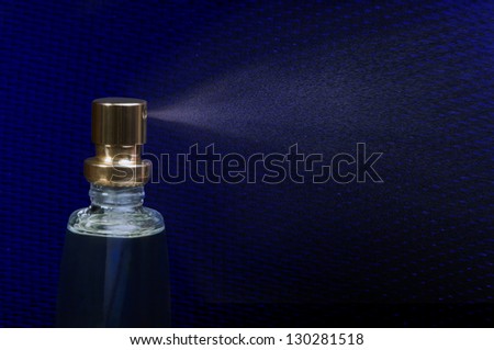 Perfume spray on blue background. Studio shot
