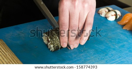 Sushi in sushi bar. Sushi making.Hands cutting sushi