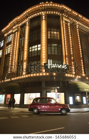LONDON, UNITED KINGDOM - CIRCA NOVEMBER 2013:Harrods department store. Facade illuminated at night. Taxi passes in front of the building