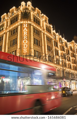 LONDON, UNITED KINGDOM - CIRCA NOVEMBER 2013:Harrods department store. Facade illuminated at night. Red bus passes in front of the building