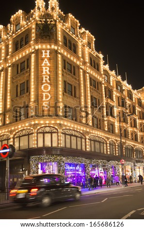 LONDON, UNITED KINGDOM - CIRCA NOVEMBER 2013:Harrods department store. Facade illuminated at night. Taxi passes in front of the building