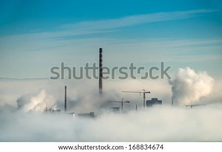 Factory chimneys and clouds of steam.Blue sky