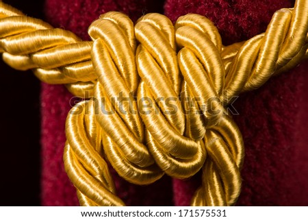 Red velvet curtain with tassel. Close up knot on rope