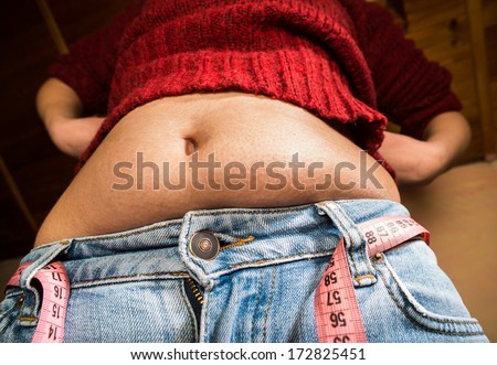Woman showing fat belly. Pink tape measure