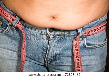 Woman showing fat belly. Pink tape measure