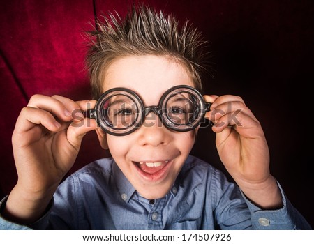 Smiled child with big glasses. Red curtain background